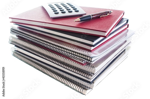 pile of school books with pen and calculator isolated on white