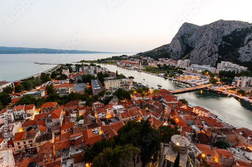 Fototapeta Naklejka Na Ścianę i Meble -  Aerial View on Illuminated Town of Omis in the Evening, Croatia