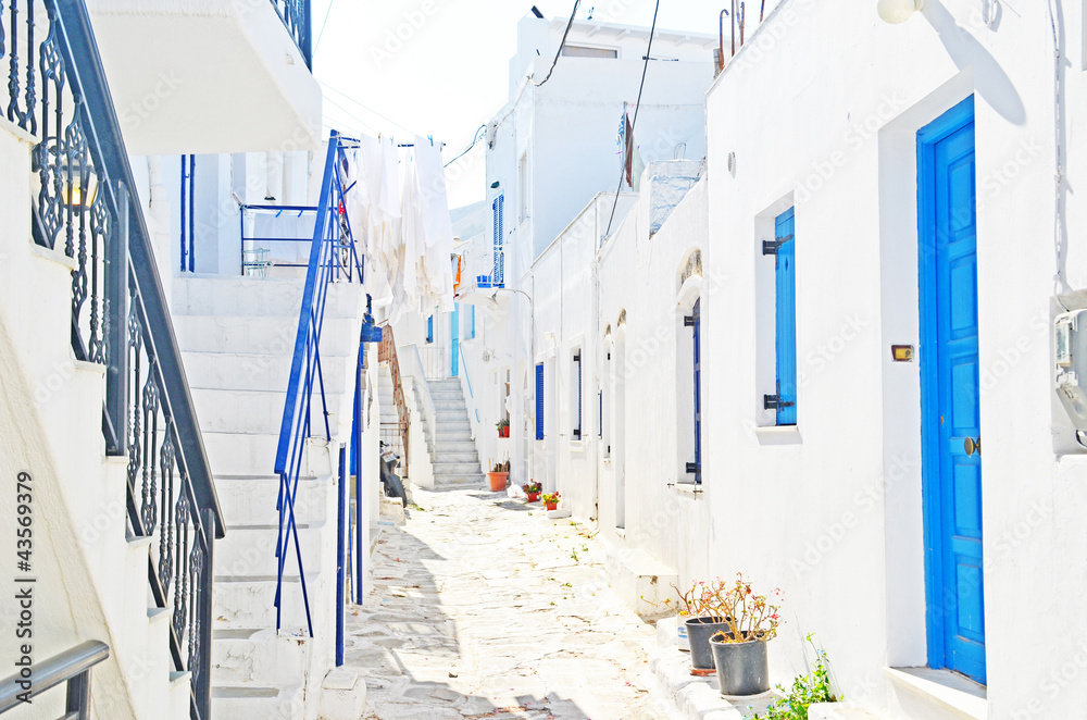Fototapeta 3D aleja na Greckiej wyspie. Urokliwa biała uliczka grecka z niebieskimi drzwiami, oknami.