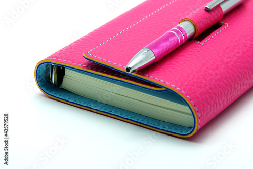 Personal Organizer in Pink Color With Ballpoint Pen on White Bac