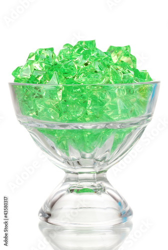 A glass with green decorative stones isolated on white