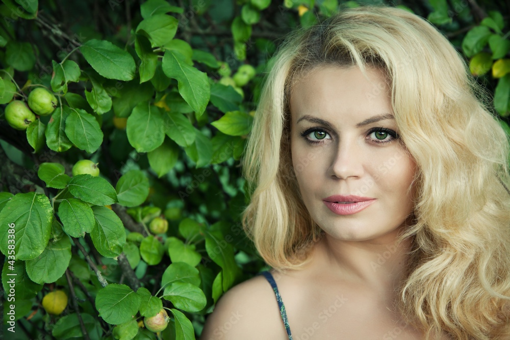 Beautiful blonde woman next to apple tree with selective focus Beautiful blonde woman next to apple tree with selective focus