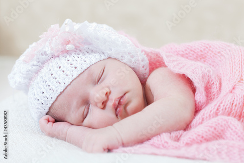 newborn girl sleeps under a knitted pink cape