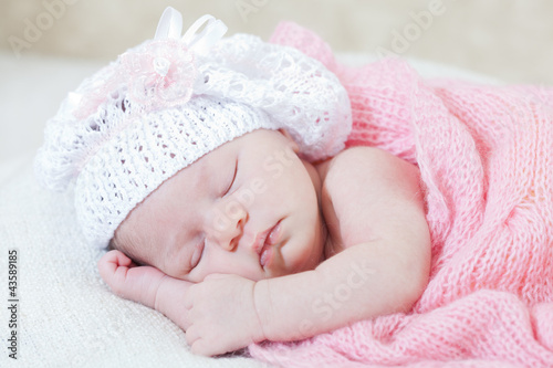 newborn girl sleeps under a knitted pink cape