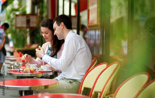 Happy couple eating macaroons in a Parisian outdoor cafe