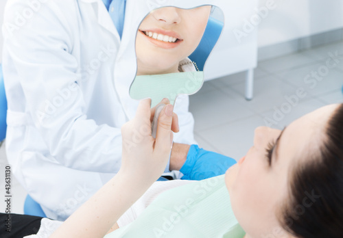The patient admires her smile looking at the mirror