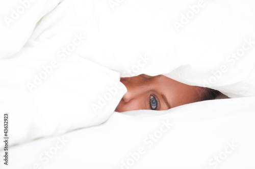 young woman in bed under blanket