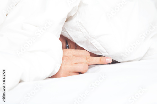 woman under blanket shows the middle finger