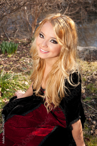 Beautiful blonde woman in vintage dress sitting in the park