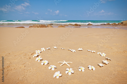 Сердце из цветов франжипани на песчаном пляже