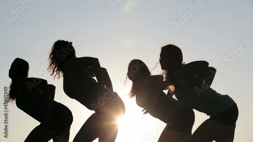 Team of four dancers dancing over sun together