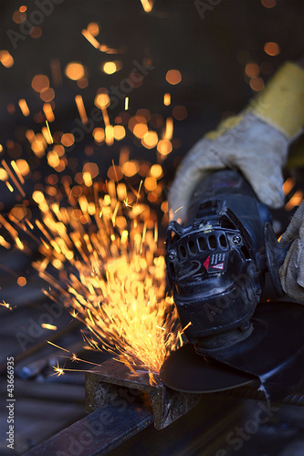 Worker cutting metal with many sharp sparks