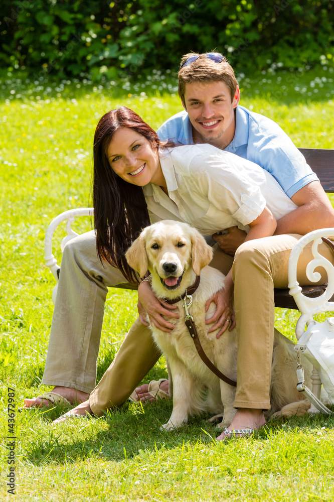 Couple sitting with golden retriever in park