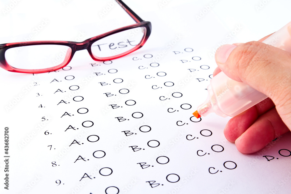 Hand on pen choosing the test list and glasses on the examinatio Hand on pen choosing the test list and glasses on the examinatio