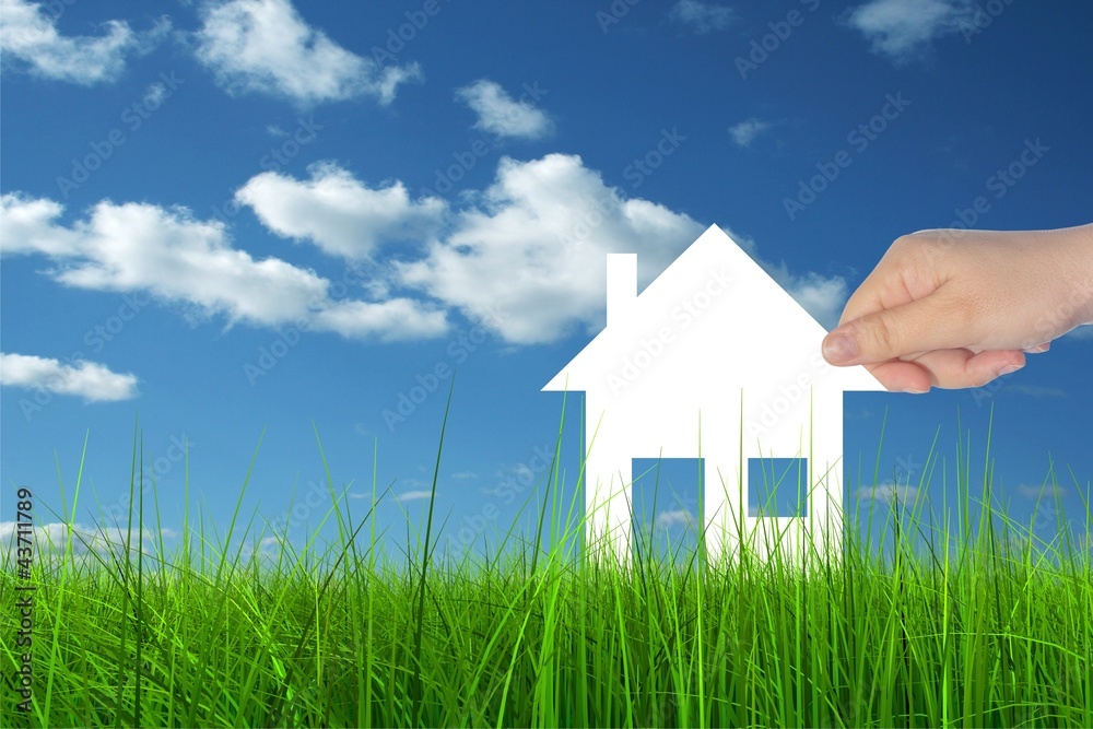 Conceptual white house held in hand in green grass Conceptual white house held in hand in green grass