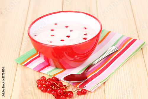 Yogurt with redcurrant on wooden table photo