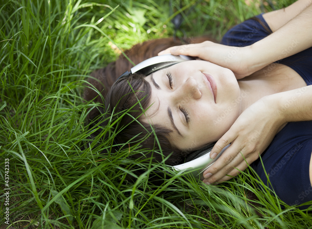 Young fashion girl with headphones at green spring grass. Young fashion girl with headphones at green spring grass.