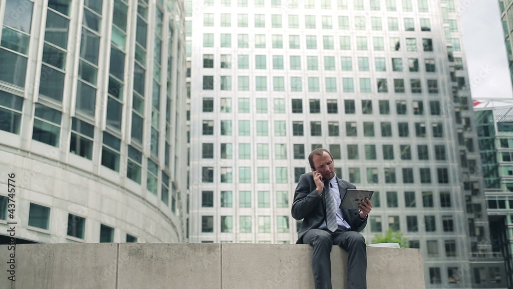 Young businessman with tablet and cellphone in the city