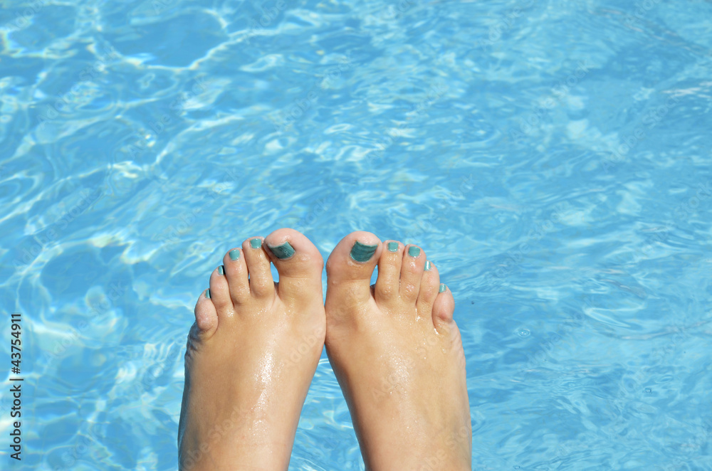 female foot with blue nails in the pool