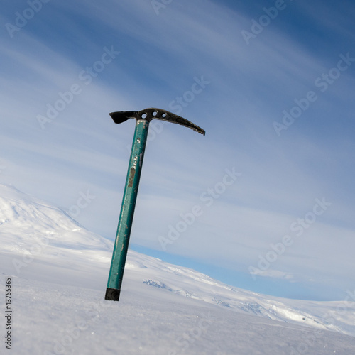 Ice axe with snow-capped mountain in the background