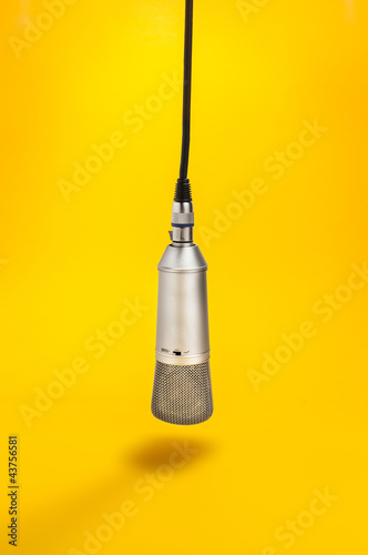 Microphone hanging from above on yellow background