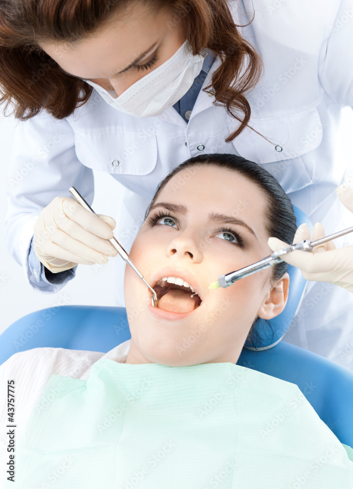 Dentist's assistant checks up the dentes of the patient