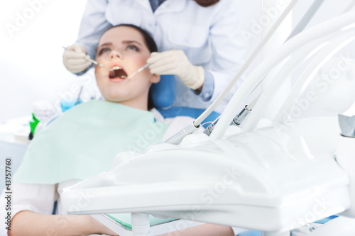 Dentist's assistant checks up the teeth of the patient.