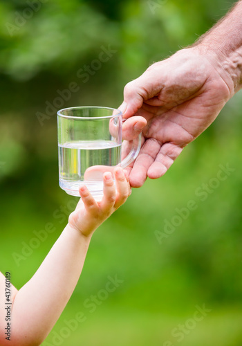 Little girl taking a glass of water from grandpa