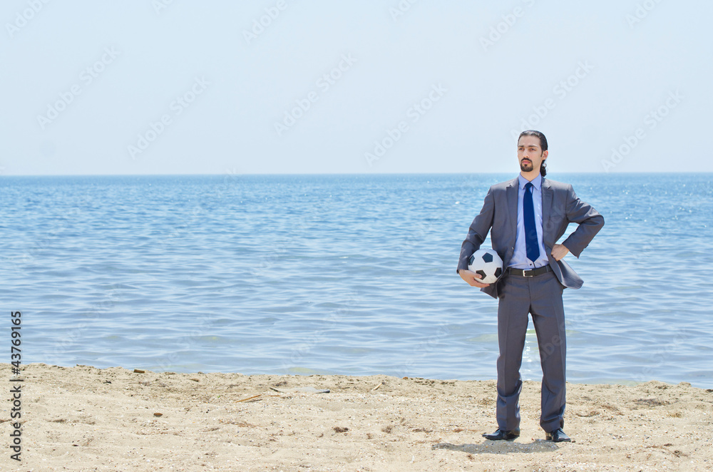 Businessman with football on beach Businessman with football on beach