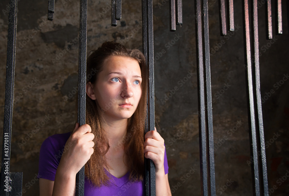 Young woman behind the bars