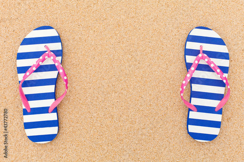 Colorful flipflop pairas a frame on beach sand