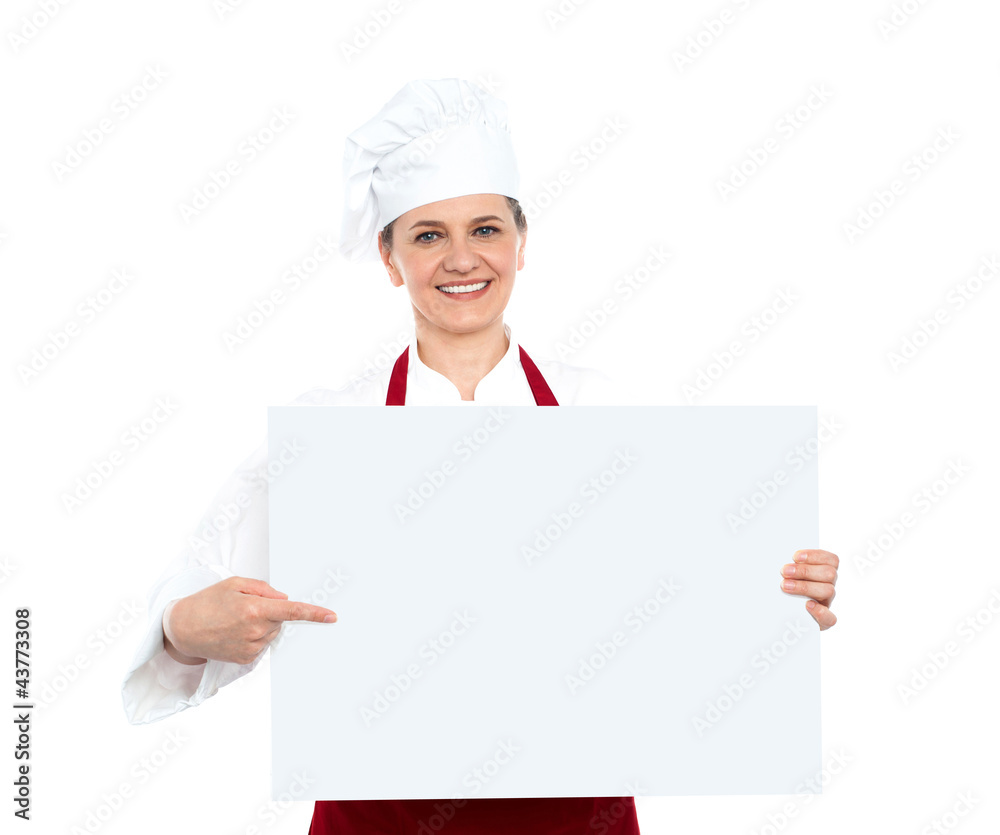 Female chef pointing towards blank whiteboard Female chef pointing towards blank whiteboard