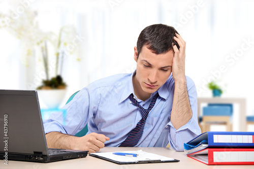 Young desperate businessman in his office looking down