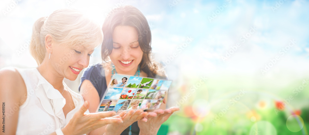 Two women sitting at park and using virtual interface to watch v Two women sitting at park and using virtual interface to watch v