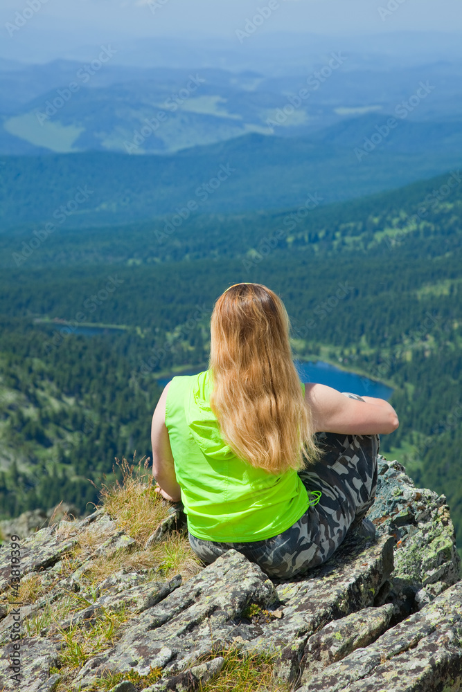 Woman sitting on mountain peak