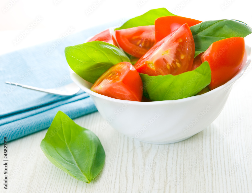 Fresh tomatoes with basil leaves in a bowl Fresh tomatoes with basil leaves in a bowl