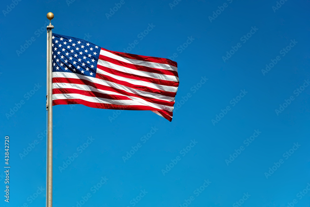 US American flag waving in the wind with beautiful blue sky in b