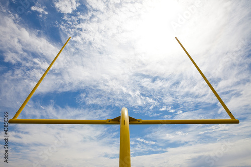 American football goal posts against clouds and blue sky photo