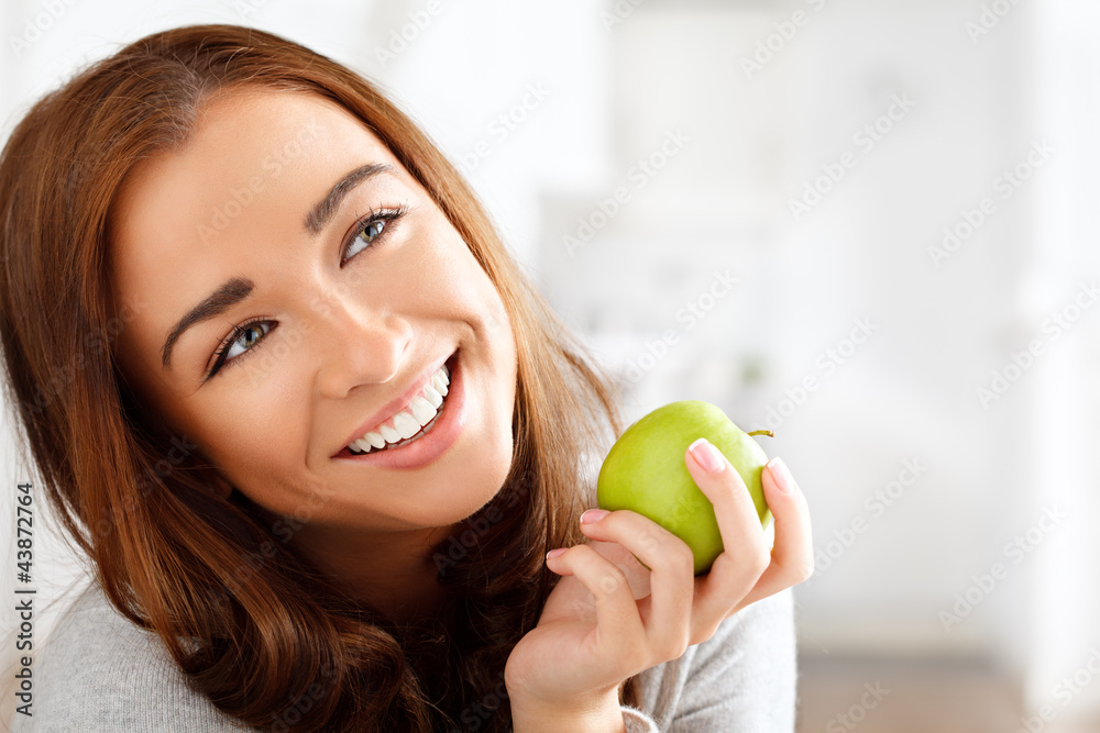 Pretty healthy young woman smiling holding a green apple Pretty healthy young woman smiling holding a green apple