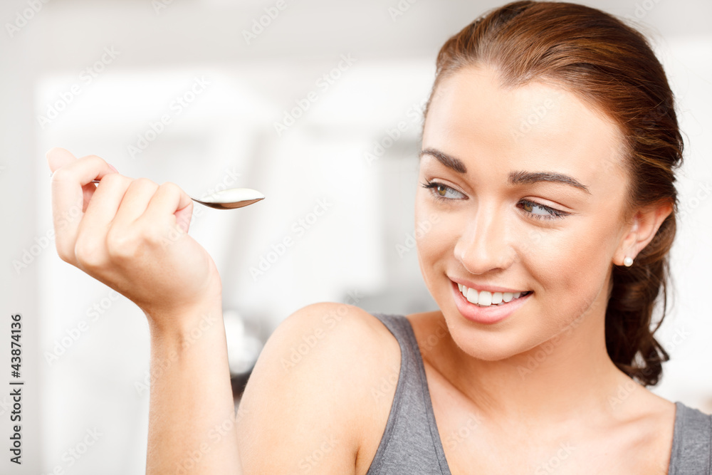 Close-up portrait of an attractive young woman eating yogurt Close-up portrait of an attractive young woman eating yogurt