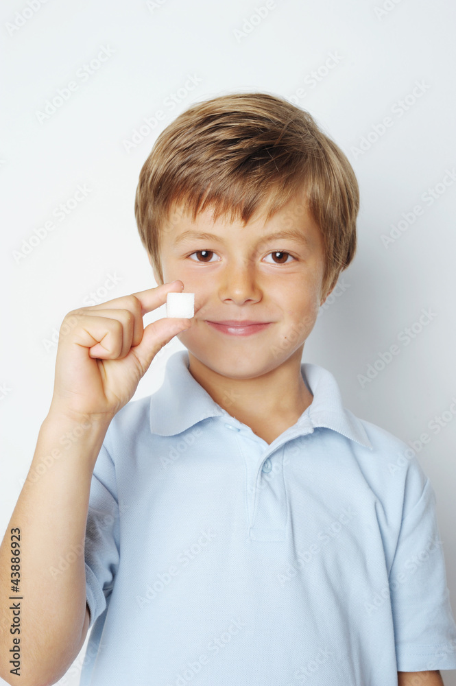 Kind hält Würfelzucker zwischen den Fingern Kind hält Würfelzucker zwischen den Fingern