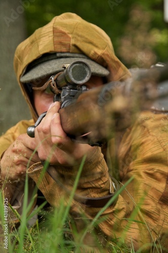 man in form of nazi sniper aims near a tree photo