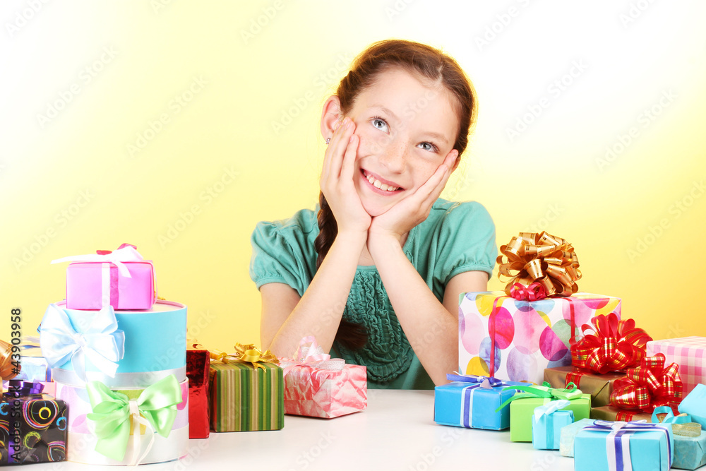 Little girl with gifts on yellow background Little girl with gifts on yellow background