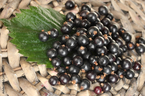 Fresh black currant on wicker mat close-up