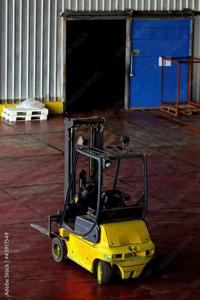 Yellow forklift parked in modern factory warehouse Yellow forklift parked in modern factory warehouse