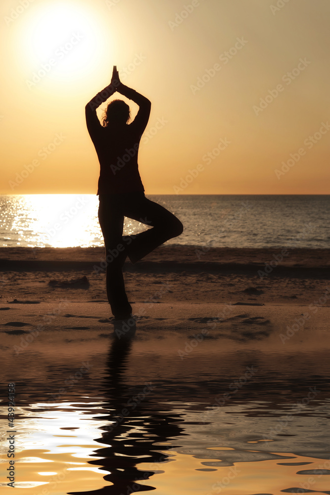Frau macht Yoga am Strand Baum Position mit Spiegelung