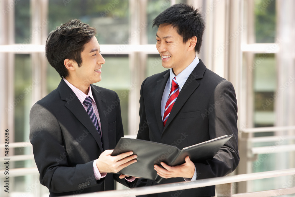 Two Businessmen Discussing Document Outside Office Two Businessmen Discussing Document Outside Office