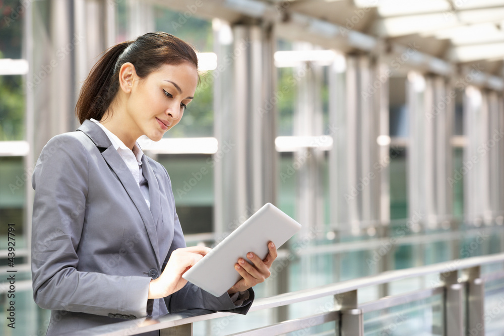 Hispanic Businesswoman Working On Tablet Computer Outside Office Hispanic Businesswoman Working On Tablet Computer Outside Office