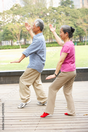 Senior Chinese Couple Doing Tai Chi In Park