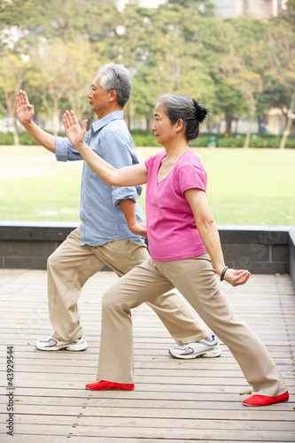 Senior Chinese Couple Doing Tai Chi In Park